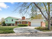 Charming home with a brick chimney, attached garage, well-maintained lawn, and a curving driveway at 588 Newark St, Aurora, CO 80010