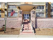 Building entrance at 495 S Dayton St, featuring stairs, brick facade, and flags at 495 S Dayton St # 1D, Denver, CO 80247