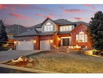 Beautiful brick home with a manicured lawn, three-car garage and charming front patio seating area at 6577 Esperanza Dr, Castle Pines, CO 80108