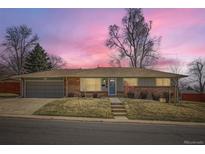 Charming ranch-style home featuring a brick facade, a well-manicured lawn, and an attached garage with an inviting curb appeal at 2822 S Zenobia St, Denver, CO 80236