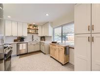 Bright kitchen featuring white cabinets, stainless steel appliances, and a butcher block island at 2822 S Zenobia St, Denver, CO 80236