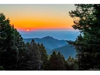 Scenic sunset view of mountains and valleys, framed by trees creating a tranquil and picturesque atmosphere at 13416 Kuehster Rd, Littleton, CO 80127