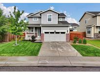 Charming gray two-story home with a manicured lawn and a two-car garage at 16048 Elizabeth St, Thornton, CO 80602