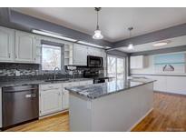 Modern kitchen featuring white cabinetry, stainless steel appliances, and a granite countertop island at 1641 Orchard Dr, Denver, CO 80221