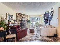 Cozy living room features a stone fireplace and access to a patio at 3576 S Depew St # 104, Denver, CO 80235