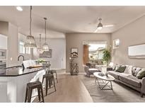Inviting living room featuring a ceiling fan, a neutral color palette and an adjacent breakfast bar at 1928 W 67Th Pl, Denver, CO 80221