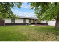 Charming home featuring a well-manicured lawn, stone accents, and mature trees at 8595 S Yarrow St, Littleton, CO 80128