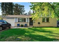 Charming home with a well-maintained lawn and inviting front porch seating area at 7479 Kendall St, Arvada, CO 80003