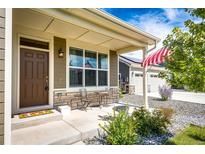 Charming front porch with stone accents, cozy seating and a welcoming entrance at 56459 E 23Rd Pl, Strasburg, CO 80136