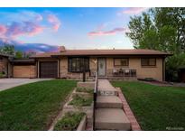 Charming brick home with a well-manicured lawn, updated siding, and cozy front porch seating at 2840 S Yates St, Denver, CO 80236