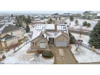 Stunning exterior features stone accents, solar panels, attached garage, and a well-manicured lawn in a snowy neighborhood at 1752 Peninsula Cir, Castle Rock, CO 80104