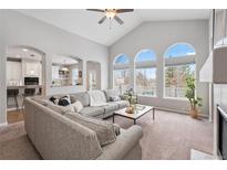 Bright living room featuring a large sectional couch, arched windows, and an open-concept design to the kitchen at 1752 Peninsula Cir, Castle Rock, CO 80104