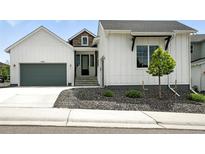 Charming home featuring white siding, a gray garage door, and well-maintained landscaping at 4855 Saddle Iron Rd, Castle Rock, CO 80104