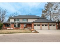 Charming two-story brick home featuring a three-car garage and well-manicured front yard at 9502 E Lake Cir, Greenwood Village, CO 80111