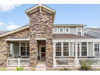 Charming two-story home featuring a stone facade, covered porch, and beautiful landscaping at 5723 S Union Ct, Littleton, CO 80127