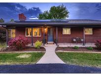 Charming brick home with manicured lawn, solar panels, and covered porch at 7112 S Platte Canyon Dr, Littleton, CO 80128