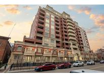 Upscale building featuring brick exterior, balconies, and parking, set against a vibrant sunset sky at 1950 N Logan St # 601, Denver, CO 80203