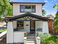 Charming home featuring a covered porch with black accents, white brick pillars, and beautiful landscaping at 400 S Gilpin St, Denver, CO 80209