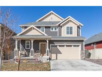 Charming two-story home featuring a covered porch, stone accents, and a two-car garage at 1079 Larkspur Dr, Erie, CO 80516