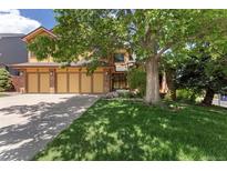 Inviting home featuring a lush front lawn and mature shade tree at 15207 W Ellsworth Pl, Golden, CO 80401