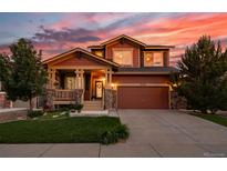 Beautiful two-story home with a well-maintained lawn and inviting covered front porch at sunset at 21502 E Idyllwilde Dr, Parker, CO 80138