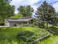 Charming home featuring a lush lawn, wood accents, and a well-manicured garden at 78 Fairway Ln, Littleton, CO 80123