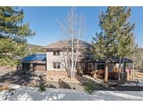 Inviting two-story home featuring a stone facade, covered porch, and a three-car garage with solar panels at 3064 Elk View Dr, Evergreen, CO 80439