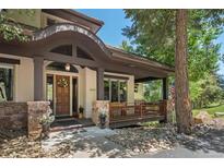 Inviting home entrance featuring a covered porch with stone accents and a charming wooden door at 3064 Elk View Dr, Evergreen, CO 80439