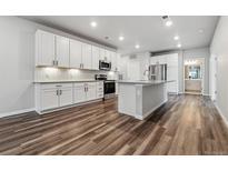 Bright, open kitchen boasts white cabinetry, stainless appliances, and a large center island with sink at 9287 Twenty Mile Rd # 108, Parker, CO 80134