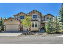 Charming two-story home with stone and stucco exterior, three-car garage, and landscaped front yard at 791 Elk Rest Rd, Evergreen, CO 80439