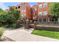 Brick exterior of a multi-story building with a landscaped walkway and fence at 1631 N Emerson St # 207, Denver, CO 80218