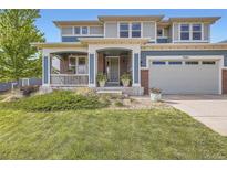 Charming two-story home featuring a welcoming front porch, lush green lawn, and attached two-car garage at 7485 S Jackson Gap Way, Aurora, CO 80016