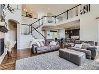 Open-concept living room with a staircase, abundant natural light, and a seamless flow to the kitchen at 7485 S Jackson Gap Way, Aurora, CO 80016