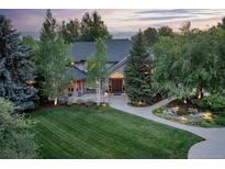 Stunning two-story home featuring mature trees, manicured lawn, and elegant stone entryway at 8439 Greenwood Dr, Niwot, CO 80503