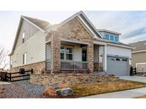 Charming home featuring stone accents, a covered porch, and a well-manicured front yard at 22773 E Narrowleaf Cir, Aurora, CO 80016