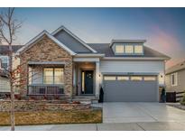 Charming home featuring a stone facade, covered porch, and well-manicured landscaping at 22773 E Narrowleaf Cir, Aurora, CO 80016