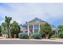 Stunning two-story brick home with white columns and manicured landscaping at 8717 Ridgepoint Dr, Castle Pines, CO 80108