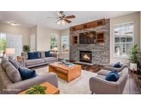 Bright living room featuring a stone fireplace, hardwood floors, and neutral decor at 3389 Willowrun Dr, Castle Rock, CO 80109