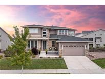 Beautiful two-story home with a manicured lawn, stone accents, and a two-car garage under a pink and purple sunset sky at 22463 E Mosey Cir, Parker, CO 80138