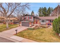 Charming two-story home with grey wood siding, a landscaped yard, a driveway, and mature trees at 7148 S Dahlia Ct, Centennial, CO 80122