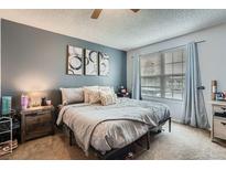 This bedroom features light blue walls, a ceiling fan, carpet and lots of natural light from the window at 14344 E Hawaii Cir # B, Aurora, CO 80012