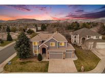 Charming two-story home featuring a well-maintained lawn, three-car garage and mountain views at sunset at 15907 W 72Nd Dr, Arvada, CO 80007
