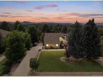 Lovely aerial view of home with mature landscaping, a long drive, and mountain views at sunset at 1025 S Butler Way, Lakewood, CO 80226