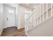 Bright entryway with a white door, wood floors, and a staircase with white railing at 3352 N Highlands Creek Pkwy, Aurora, CO 80019
