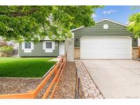 Charming single-story home with a green exterior, a white garage door, and a well-maintained front yard at 5007 S Richfield Cir, Aurora, CO 80015