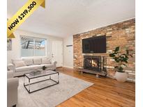 Inviting living room features a brick fireplace, hardwood floors, and a comfortable seating area with natural light at 155 S Pennsylvania St # 308, Denver, CO 80209