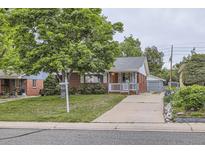 Charming brick home featuring a well-manicured lawn, covered porch, and spacious driveway at 1824 S Columbine St, Denver, CO 80210