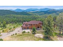 Stunning exterior elevation with a two-car garage nestled amongst lush forestry and picturesque mountain views at 31231 Red Hawk Trl, Conifer, CO 80433
