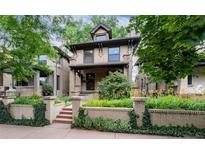 Charming brick home with mature landscaping, a covered front porch, and classic architectural details at 1308 York St, Denver, CO 80206