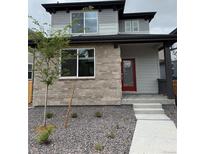 Charming two-story home featuring stone accents, a red front door, and a neatly landscaped front yard at 21031 E 63Rd Dr, Aurora, CO 80019